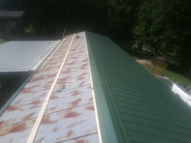 Old rusted panels beside newly installed green metal roofing — Wind Damage Roof Repair by Roofing Brothers in Menomonee Falls