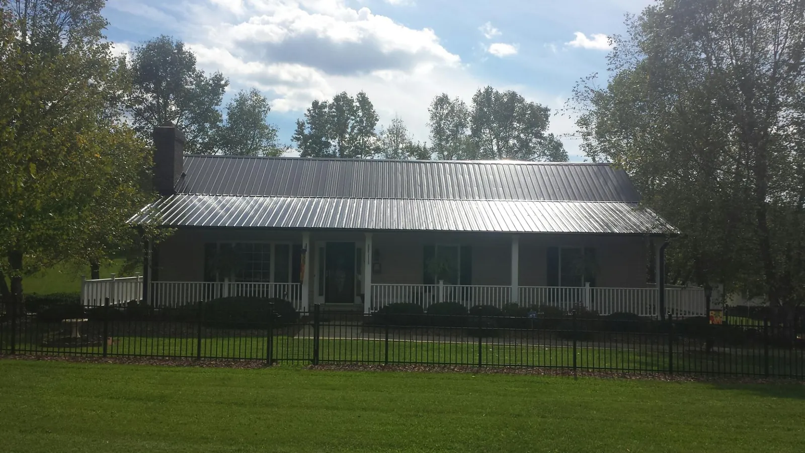 Gray metal roof on a brick ranch with a full width front porch — Gutter Guard Installation work by our crew in Menomonee Falls